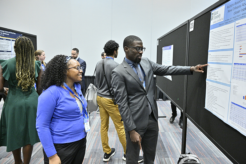 presenter shows his poster to an Annual Meeting attendee