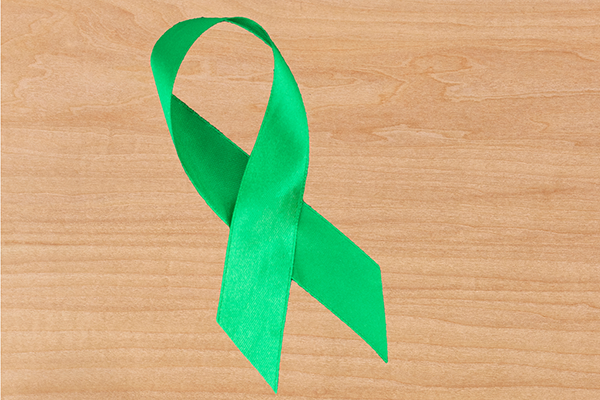 Green ribbon on wooden background