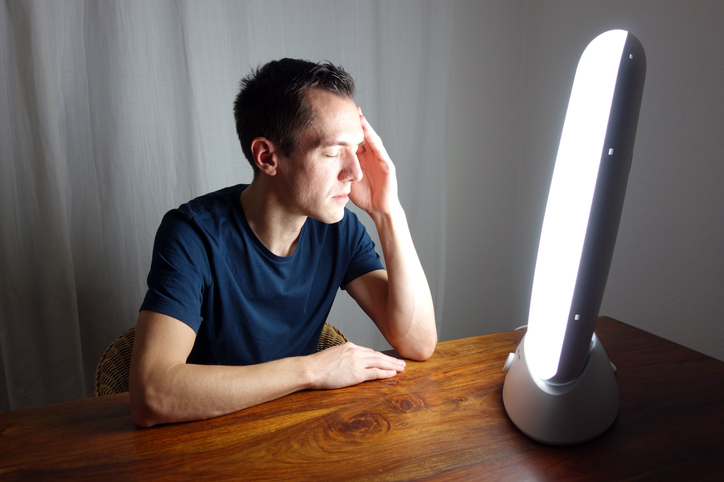 man sitting in front of a therapy light