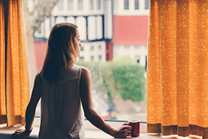 woman with cup looking out window